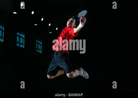 Junger Mann springt hoch In die Luft während einer Partie Badminton Stockfoto