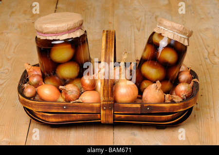 Zwei Gläser von zu Hause gemacht eingelegte Zwiebeln umgeben durch Beizen Zwiebeln in Trug auf rustikalen Küchentisch UK September Stockfoto
