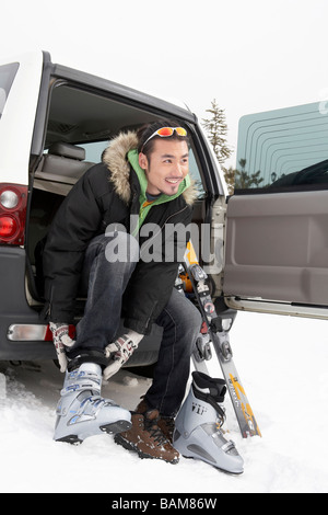 Mann sitzt im Auto, Skischuhe anziehen Stockfoto