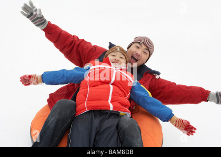 Vater und Sohn Reiten auf aufblasbaren Snow-Tube Stockfoto