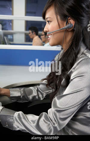 Frau In einem Callcenter einen Kopfhörer tragen und lächelnd Stockfoto