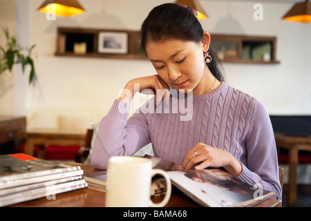 Junge Frau sitzt im Cafe mit Büchern Stockfoto