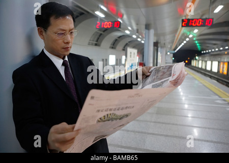 Geschäftsmann Zeitunglesen im Bahnhof Stockfoto