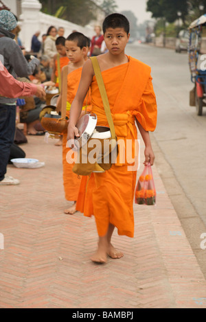 Neuling buddhistischen Mönchen Almosen in den frühen Morgenstunden entlang der Hauptstraße in Louang Phabang Laos Stockfoto