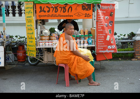 buddhistischer Mönch, der in einer mobilen Küche auf dem Gelände des Wat Phra Singh Tempels Chiang Mai sitzt Stockfoto