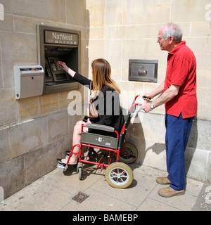 Weibliche ungültig Rollstuhlfahrer und männliche Pfleger mit einer Bank Bargeld darauf England UK Stockfoto