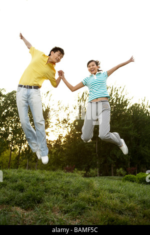Junges Paar Hand in Hand und springen im Park Stockfoto