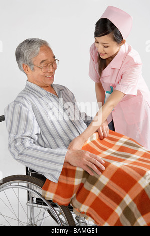Krankenschwester, die Festsetzung der Decke für Menschen im Rollstuhl Stockfoto