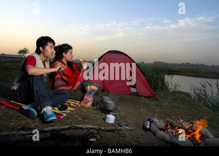 Junges Paar mit Feuer und Zelt Camping Stockfoto