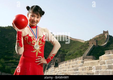 Turnerin auf der chinesischen Mauer stehend mit einem Ball Stockfoto