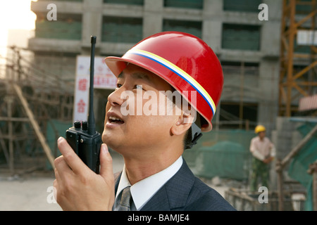 Geschäftsmann In einer Baustelle mit einem Schutzhelm und Walkie-Talkie Stockfoto