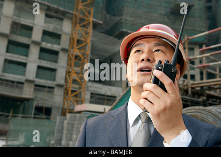 Geschäftsmann In einer Baustelle einen harten Hut mit einem Walkie-Talkie Stockfoto