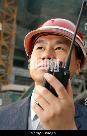 Geschäftsmann In einer Baustelle einen harten Hut mit einem Walkie-Talkie Stockfoto