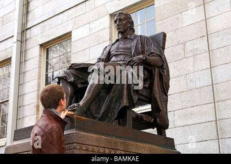 Ein Schüler berühren den linken Schuh von John Harvard als Glücksbringer in Examens, Harvard University, Cambridge, Massachusetts, USA Stockfoto