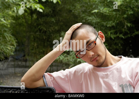 Junger Mann sitzen auf Stuhl Blick in die Kamera Stockfoto