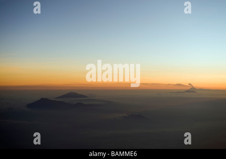 Einige Bergspitzen spähte durch eine Decke aus Wolken gesehen von einer Flugzeugkabine s Stockfoto