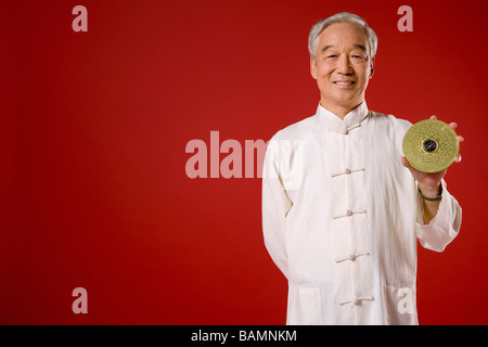 Älterer Mann, der riesige chinesische Münze hält Stockfoto