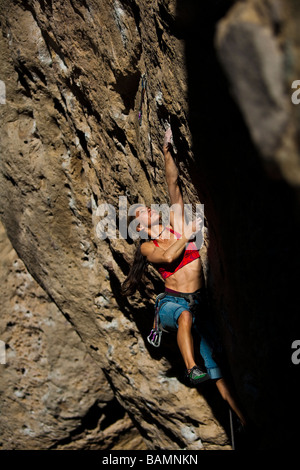 Weibliche Kletterer konzentriert sich auf ihre nächsten Schritte, wie sie ihren Weg auf einer steilen Klippe in Malibu Creek State Park in Kalifornien kämpft Stockfoto