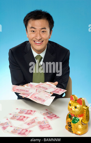 Junger Geschäftsmann mit Banknoten und Maneki Neko Stockfoto