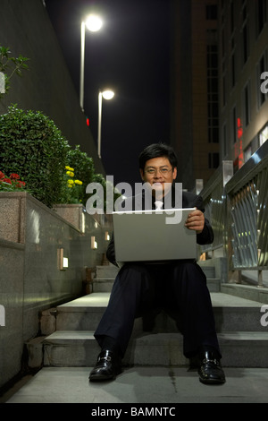 Geschäftsmann mit Laptop sitzend auf Schritte Stockfoto