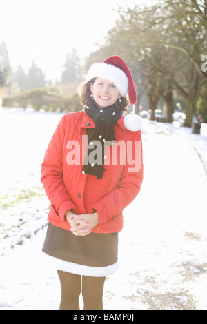 Lächelnde Frau in einem Park mit Weihnachtshut Stockfoto