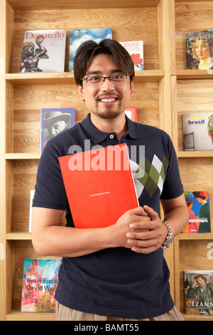 Man Holding Buch in Bibliothek Stockfoto
