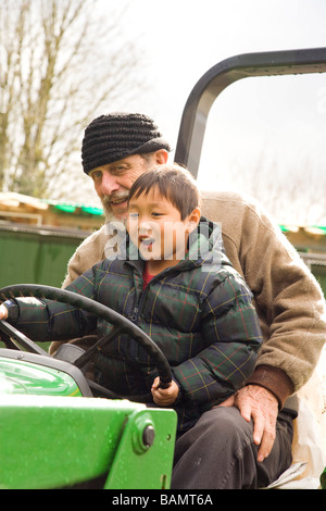 Großvater mit Enkelkind auf Traktor Stockfoto