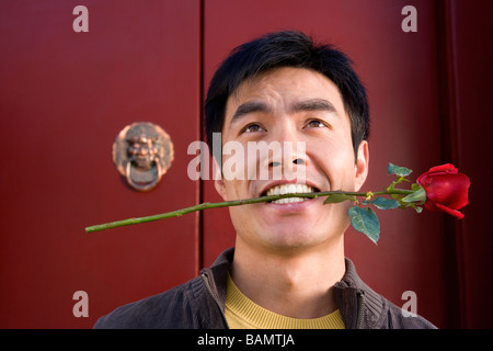 Junger Mann warten vor der Tür hält eine Rose im Mund Stockfoto