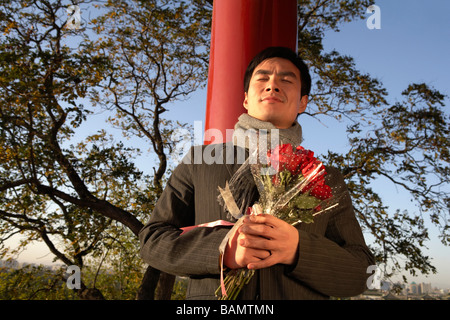 Junger Mann gelehnt Pole mit Blumenstrauß Stockfoto