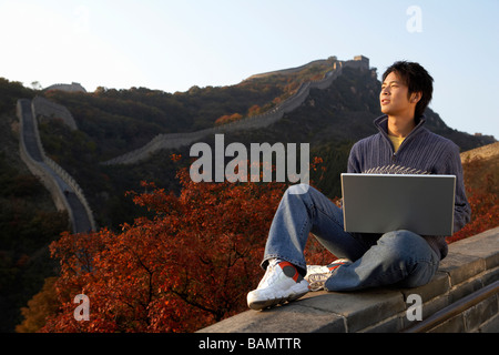 Junger Mann nutzt Laptop auf der chinesischen Mauer Stockfoto