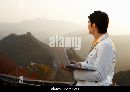 Junger Mann nutzt Laptop auf der chinesischen Mauer Stockfoto