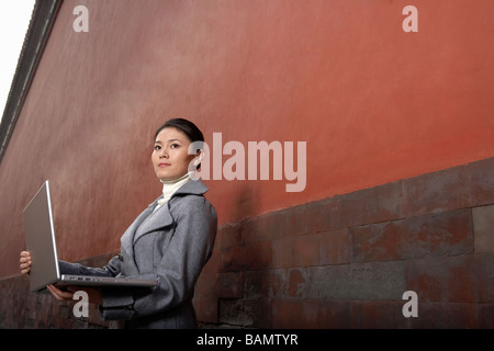 Frau stand neben Gebäude mit Laptop Stockfoto