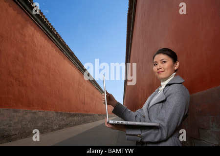 Frau stand neben Gebäude mit Laptop Stockfoto