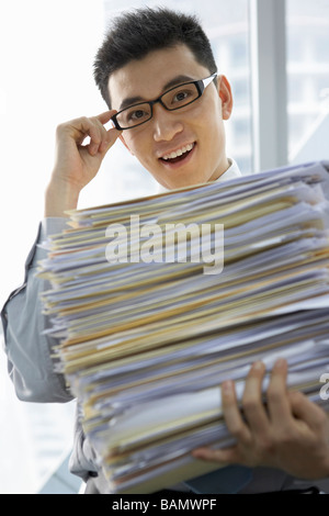 Geschäftsmann im Amt halten Haufen Arbeit Stockfoto