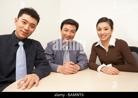 Geschäftsleute sitzen um einen Tisch, Lächeln Stockfoto