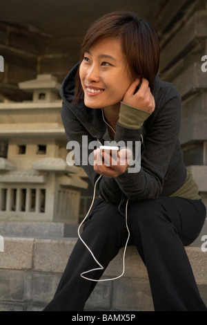 Junge Frau In Sportkleidung Kopfhörer anhören Stockfoto