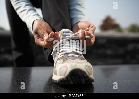 Junge Frau, die ihre Schnürsenkel zu binden Stockfoto