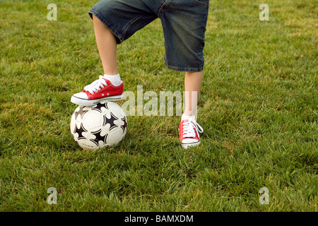 Junge stand mit einem Fuß auf Fußball Stockfoto