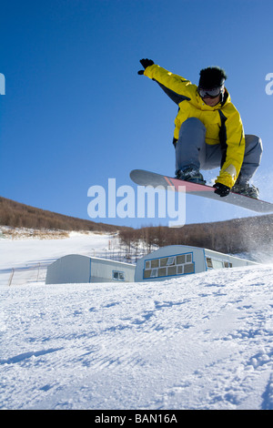 Junger Mann auf seinem Snowboard mitten in der Luft Stockfoto