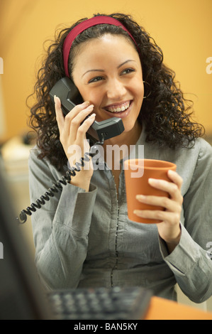 Junge Geschäftsfrau, trinken Kaffee und Gespräch am Telefon Stockfoto