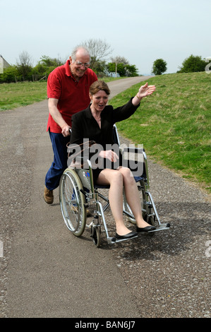 Ältere Pfleger schob Frau in einem Rollstuhl in der englischen Landschaft UK Stockfoto