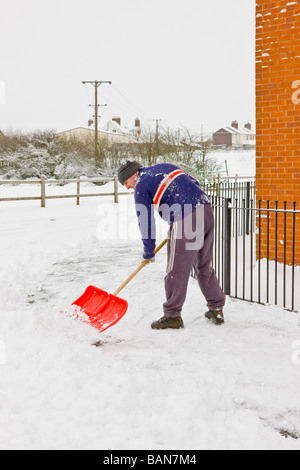 ein Mann Schaufeln Schnee von einem Weg vor einem Haus Stockfoto