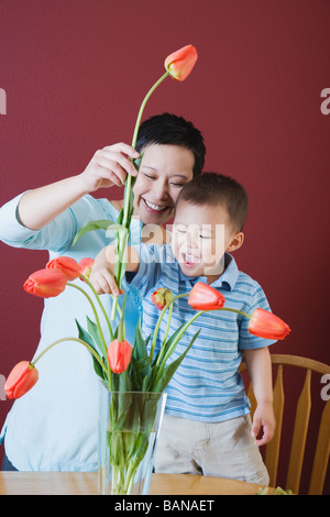 Mutter und junge Sohn setzen Blumen in vase Stockfoto