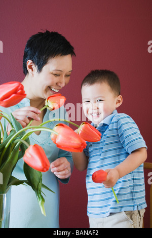 Mutter und junge Sohn setzen Blumen in vase Stockfoto