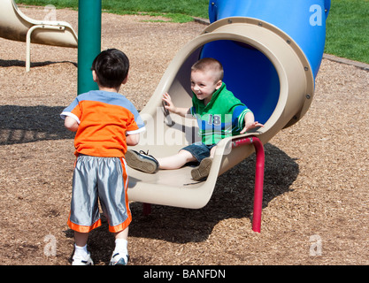 Zwei Jungen spielen im Park am Ende eines Rohres schieben. Stockfoto