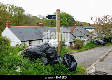 schwarzer Kunststoff Mülltüten links außen Cottages in Cornwall, Großbritannien Stockfoto