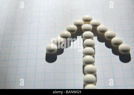 Folsäure-Pillen auf Zeichenpapier mit Maßeinteilung ausgerichtet, um einen Pfeil zu bilden. Stockfoto