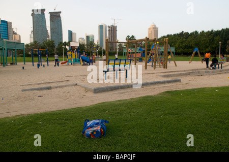 Kinderspielplatz an der Corniche in Doha Katar mit Wolkenkratzern des Financial District am Horizont. Stockfoto