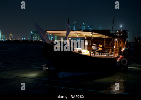 Arabische Dhau, festgemacht an der Corniche in der Nacht mit dem Finanzviertel im Hintergrund Stockfoto