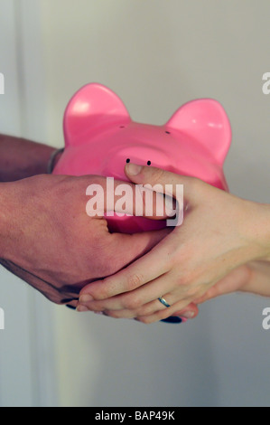 junge weiße paar Hände halten Piggy Sparkasse Stockfoto